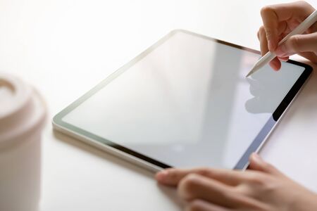 Women hand are using the tablet on the desk. Take your screen to put on advertising.