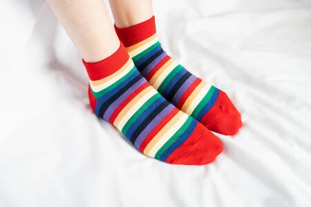 Women's legs in socks colors alternating, side stand on white fabric floor.の写真素材