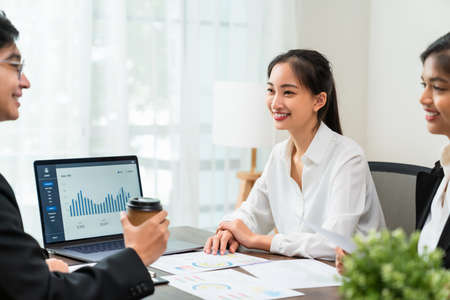 Teamwork Brainstorming Meeting and new startup project in the workplace, Smily Asian businesspeople working on laptop with graph documents.の写真素材