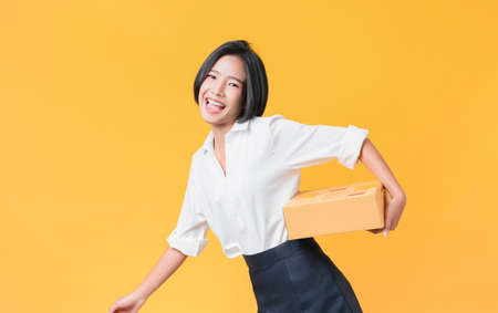 Young smiling asian woman hands showing cardboard boxes on light orange background.の写真素材