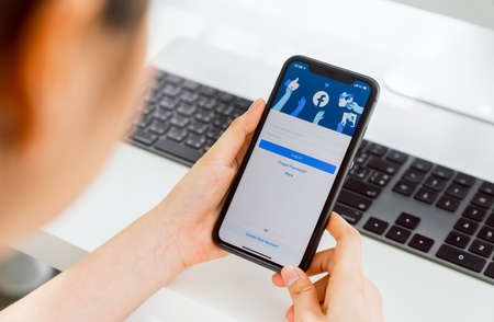Bangkok, Thailand - September 5, 2020 : Woman hand is pressing the Facebook screen on apple iphone 11, Social media are using for information sharing and networkingのeditorial素材