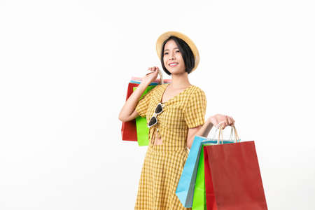 Young smiling asian woman holding multi coloured shopping bags and looking on white background.の写真素材