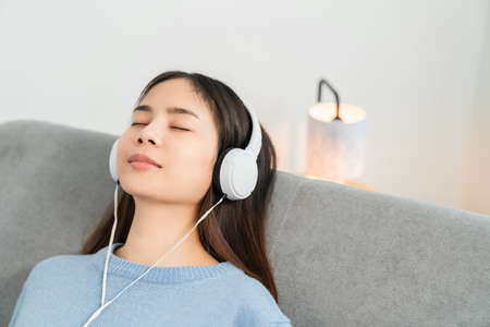 Asian woman of happy smiling are listening to music from white headphones on vacation in the house.