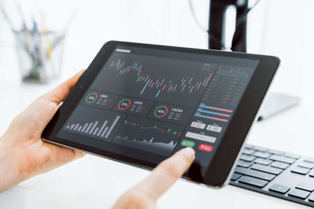 Stock exchange market concept, Hand trader touch on digital tablet with graphs analysis candle line...