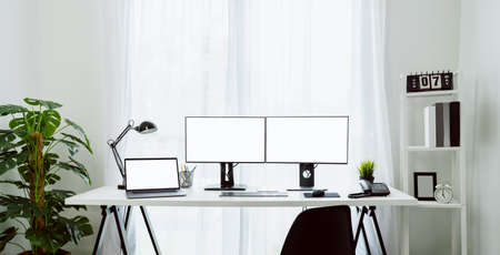 Nice desk in home, computer and laptop with blank screen on table in home on the day light shone in the afternoon.の写真素材