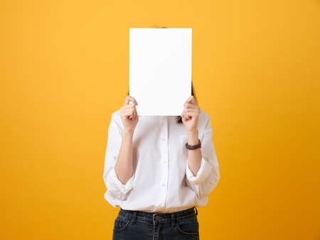 Young woman holding blank paper on the yellow background. for advertising signs.の写真素材