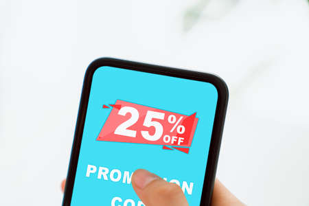 Woman holding smartphone to enter the code to get a discount from the store. Concept of providing marketing services on internet for easy access to information.の写真素材