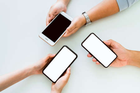 Hand holding smartphone mockup of blank screen on the table. Take your screen to put on advertising.の写真素材
