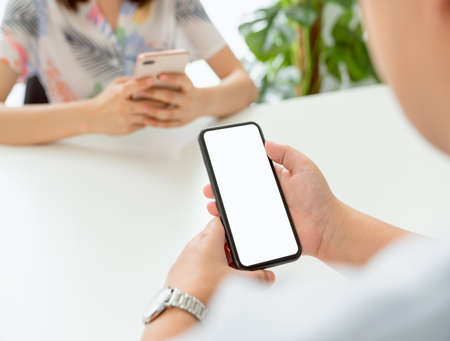 friends group holding smartphone mockup of blank screen on the table. Take your screen to put on advertising.の写真素材