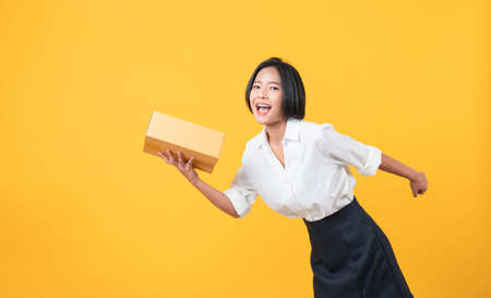 Young smiling asian woman hands showing cardboard boxes on light orange background.の写真素材