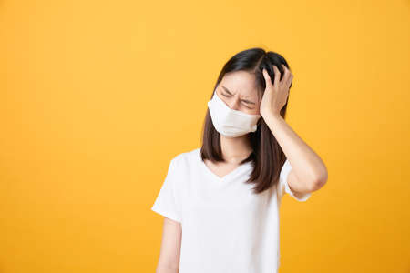Asian women wear masks to protect disease and the headache from a virus on orange background.の写真素材