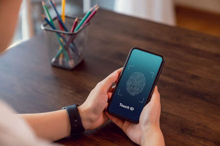 Woman hands scanning fingerprint on smartphone to unlock mobile phone on the table, Concept security in identity technology.の写真素材