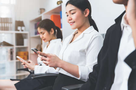 Asian business people sitting on the chair at office using smartphone and contact with customers. Concept working teamwork.の写真素材