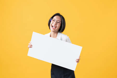 Young Asian woman holding blank paper with smiling face and looking on the orange background. for...