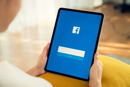 Bangkok, Thailand - September 5, 2020 : Woman hand holding digital tablet and pressing the Facebook screen on apple ipad, Social media are using for information sharing and networking.のeditorial素材