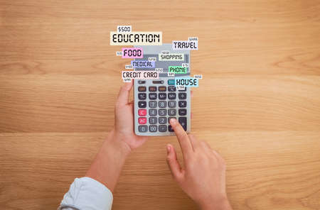 Woman holding and press calculator to calculate income expenses and plans for spending money on home office.の写真素材