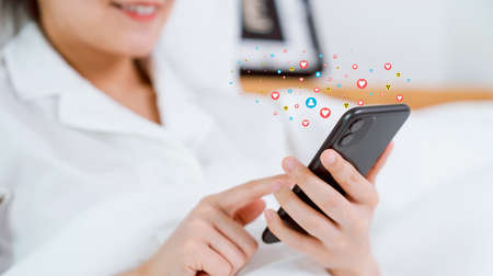 Smiling happily woman hand using smartphone and show heart icon social media. Concept social...