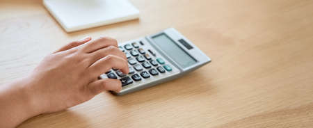 Woman press calculator to calculate income expenses and plans for spending money on home office.の写真素材