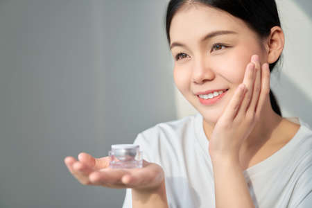 Smile Asian woman skin beauty and hand holding a product cream bottle for spa products and make up. The skin is smooth and beautiful.の写真素材