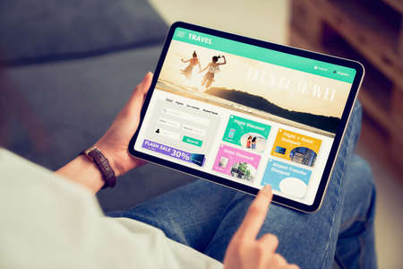 Hands holding digital tablet with application booking flight travel search ticket holiday and hotel on website discounted price, concept technology online marketing and promotion.の写真素材