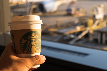 Chiba, Japan - March 24, 2019: Hand holding Starbucks coffee cup with brand logo at Narita International Airport, Chiba, Japan.のeditorial素材
