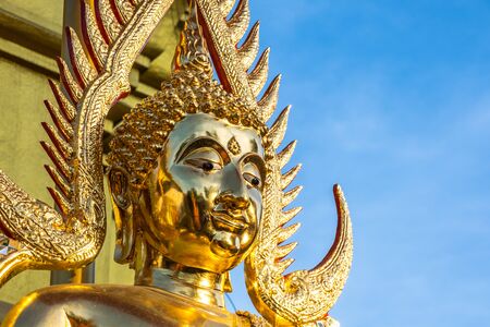 The golden Buddha face and the Buddhist yellow flag in outdoor of the temple in Thailand with the...