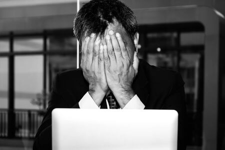 An Asian male businessman is sad and crying in front of the computer laptop for his failure...