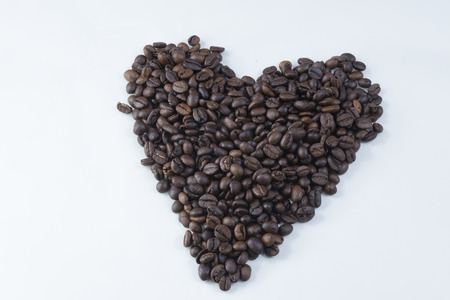 Heart shape roasted coffee beans with coffee beans background isolated on white.の写真素材