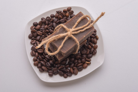 Traditional home made natural coffee soap with a pile of coffee beans on the background suggesting healthy organic non toxic wash productsの写真素材
