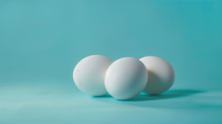 Three white eggs on a blue backgroundの素材