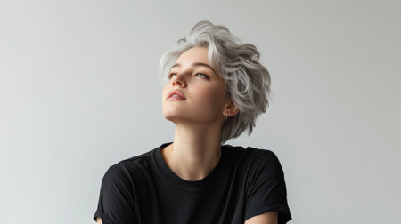Close up of beautiful woman with white skin, grey short hair, wavy hair and a clear black t shirt, isolated in a light white studio. Portrait person.の素材
