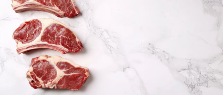 Three raw tomahawk steaks on white marble background.の素材