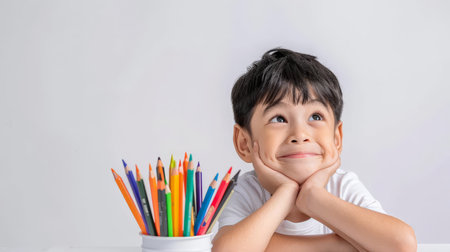 Cute asian boy thinking with color pencils on white backgroundの素材