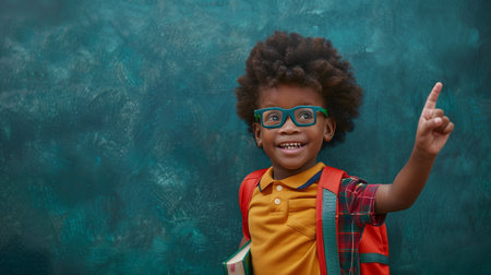 cheerful african american schoolboy in eyeglasses pointing at copy spaceの素材