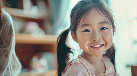 Portrait of cute little asian girl smiling and looking at camera at homeの素材