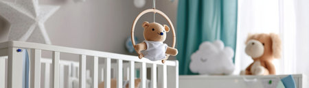 A crib with a teddy bear hanging from the rail. The crib is white and the teddy bear is brownの素材