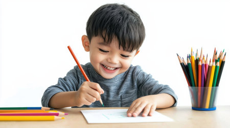 A young boy is drawing with a pencil and smiling. Concept of joy and creativity as the child engages in an artistic activityの素材