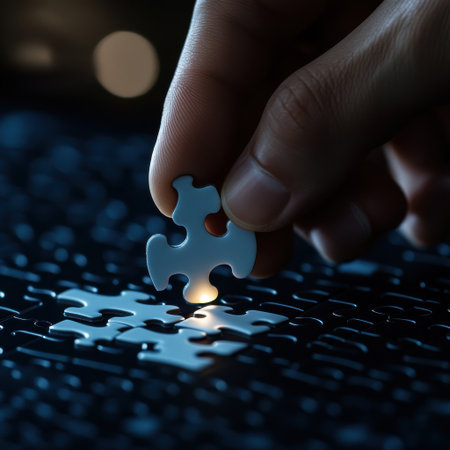 A hand is holding a piece of a jigsaw puzzle. The puzzle piece is missing and the hand is about to place it back into the puzzleの素材