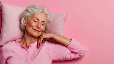 A woman is laying on a pink pillow with her head resting on her hand. She is smiling and she is in a relaxed stateの素材