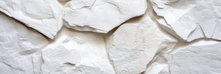 A white stone wall with a rough texture. The wall is made up of many small rocks, and it is a part of a larger structure. Scene is one of ruggedness and strengthの素材