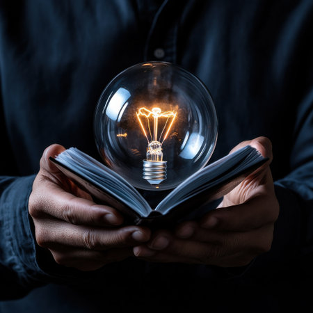 A person is holding a book with a light bulb inside of it. The light bulb is glowing and the book is open. Concept of curiosity and wonderの素材
