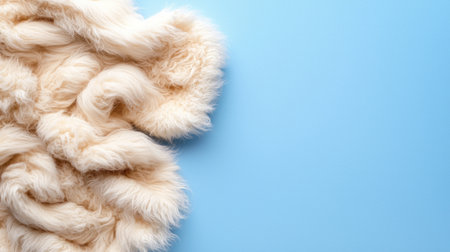 A fluffy white blanket is on a blue background. The blanket is made of wool and has a fuzzy texture. The blue background gives the image a calm and peaceful moodの素材
