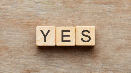A wooden block with the letters Y, E, S, and a cross through it. The letters are arranged in a way that they spell out the word "yes". Concept of determination and confidenceの素材