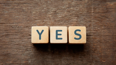 A wooden block with the letters Y, E, and S arranged in a cross shape. The arrangement of the letters creates a sense of unity and completeness, as if they are all connected to each otherの素材