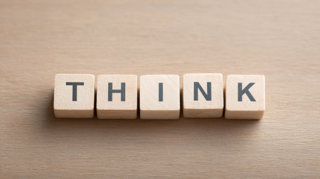A wooden block with the word "think" written on it. The block is placed on a wooden surface, and it is a puzzle or a game piece. The word "think" is written in a cursive styleの素材