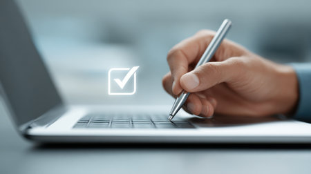 A person is writing on a laptop with a pen. The laptop has a check mark on itの素材