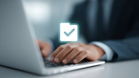 A man is typing on a laptop with a check mark on the screen. Concept of accomplishment or satisfaction, as the check mark indicates that the task has been completed successfullyの素材