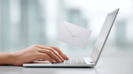A person is typing on a laptop with an envelope flying out of the screen. Concept of communication and the importance of written correspondence. The envelope represents a message that is being sentの素材