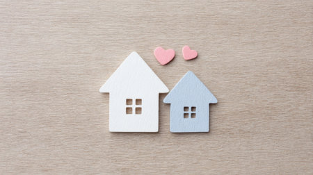Two small houses with hearts on them. The houses are on a wooden surfaceの素材