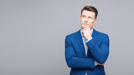 A man in a blue suit is looking to the left. He is wearing a suit and tie and he is deep in thoughtの素材